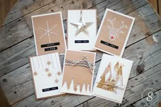 five christmas cards laid out on top of a wooden table with string and star decorations