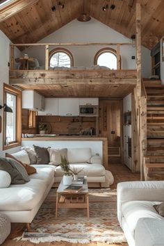 a living room filled with white furniture and wooden stairs leading up to the top floor