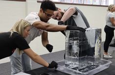 two men and a woman working on an ice sculpture