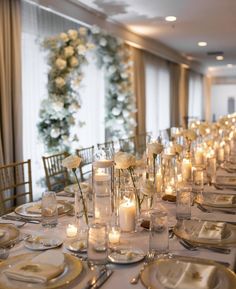 a long table is set with white flowers and candles for an elegant dinner or reception