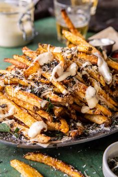 french fries covered in melted cheese and parmesan on a plate with dipping sauce