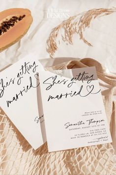 two wedding cards sitting on top of a table next to a slice of melon