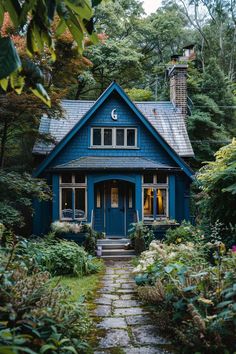 a blue house surrounded by greenery and trees