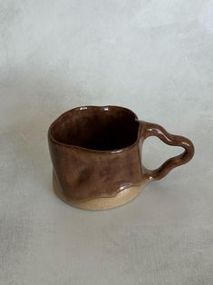 a brown ceramic cup sitting on top of a white table