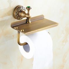 a gold toilet paper holder with two rolls of toilet paper hanging from it's side