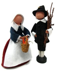 two figurines dressed in old fashioned clothes and hats, one holding a basket with carrots