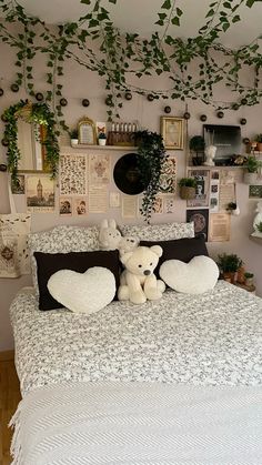 a bed with two stuffed animals on top of it and some plants hanging from the ceiling