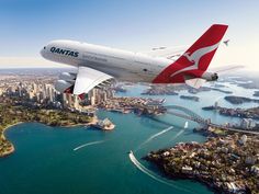 an air plane flying over the water and cityscape in sydney, australia on a sunny day