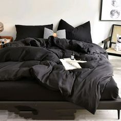 a bed with black sheets and pillows in a room