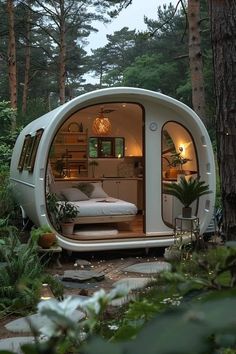 a bed in the middle of a forest with lots of trees and plants around it