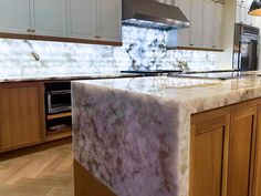 a marble counter top in a kitchen with wooden cabinets and an oven on the side