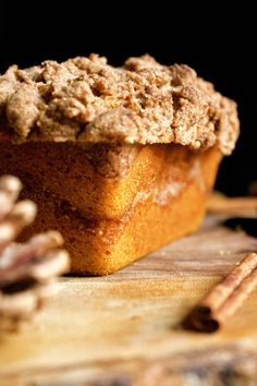 a muffin sitting on top of a wooden cutting board next to some cinnamon sticks