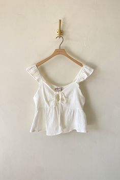 Product Details 100% Cotton Hand Wash Cold Plunging V Neckline w/ Tie Textured Material Keyhole Cutout Peplum Hem Cute Simple Tops, Sewn Tops, Cute Tops Aesthetic, Coastal Granddaughter Outfits, White Babydoll Top, Country Summer Outfits, Sabrina Carpenter Concert, Cutesy Outfit, Babydoll Tops