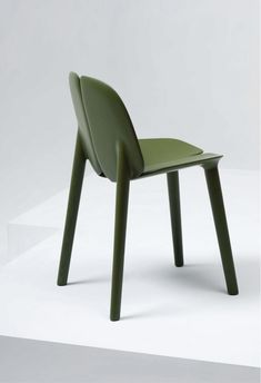 a green plastic chair sitting on top of a white floor next to a black object