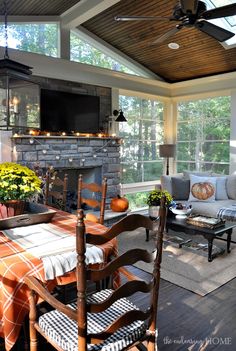 a screened porch with chairs, table and fireplace