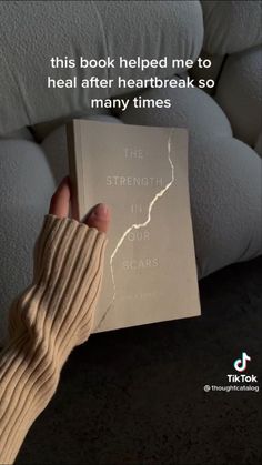 a person holding up a book in front of a couch with the caption, this book helped me to heal after heart break so many times