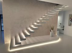 a white staircase with lights on it in a modern house or office area, next to a potted plant