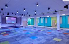 an empty room with colorful carpeting and blue doors on the walls is lit by recessed lights