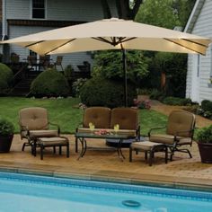 an umbrella over a table next to a swimming pool with chairs and tables around it