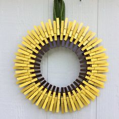 a yellow and brown wreath hanging on the side of a white door with a green plant