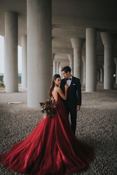 a man and woman in formal wear standing next to each other under an overpass