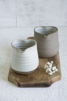 two white vases sitting on top of a wooden tray