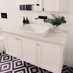 a bathroom with black and white flooring and a vase filled with flowers on the counter