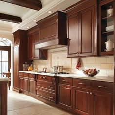 a large kitchen with wooden cabinets and white counter tops, along with tile flooring