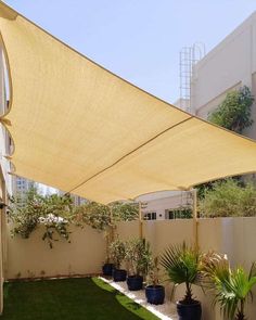 an outdoor area with grass, potted plants and shade sail