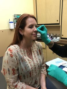 a woman getting her teeth checked by a doctor in a dental office with gloves on