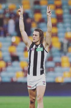 a male afl player is holding his hands up in the air