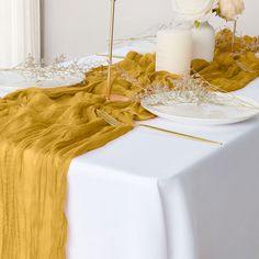 a table topped with a white vase filled with flowers and two gold forks sitting on top of it