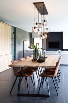 a dining room table with chairs and lights hanging from it's centerpieces