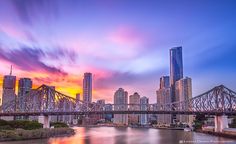 the city skyline is reflected in the water as the sun sets over the sydney bridge