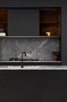 a black kitchen with marble counter tops and cabinets