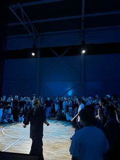 two men standing on top of a basketball court in front of a crowd at night