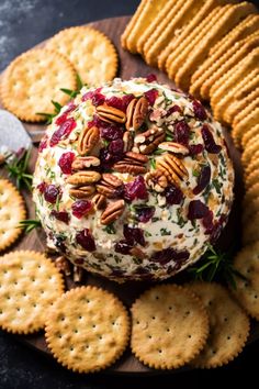 cheese ball with cranberry sauce and pecans on a platter surrounded by crackers