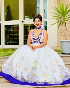 a woman in a white and blue dress sitting on steps