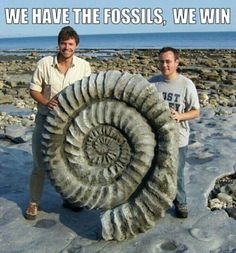 two men standing next to a large stone object