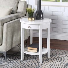 a living room with a couch, chair and table in front of a window that has a vase on it