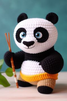 a crocheted panda bear holding a bamboo stick