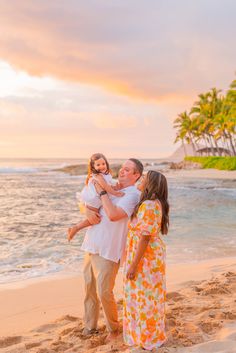 a family on the beach at sunset with palm trees and water in the back ground