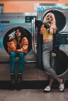 two women sitting in front of a washing machine