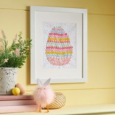 a pink bunny sitting on top of a shelf next to a potted plant and some eggs