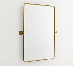 a mirror mounted to the side of a wall with a gold frame and brass fittings