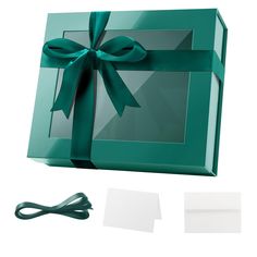 an open green gift box with a ribbon on the top and two pieces of paper underneath it