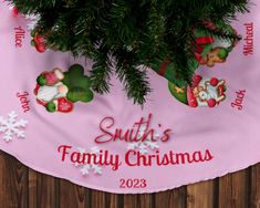 a pink christmas tree skirt with santa's family and friends on it, hanging from a wooden fence