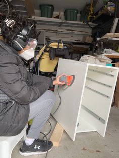 a person in a garage working on a piece of furniture with an electric driller