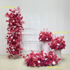 two vases with pink and red flowers in them on a table next to a white wall