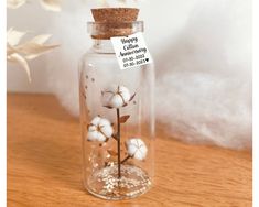 a glass jar filled with cotton flowers on top of a wooden table